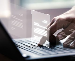 mains qui écrivent sur le clavier d'un ordinateur avec des fiches holographiques
